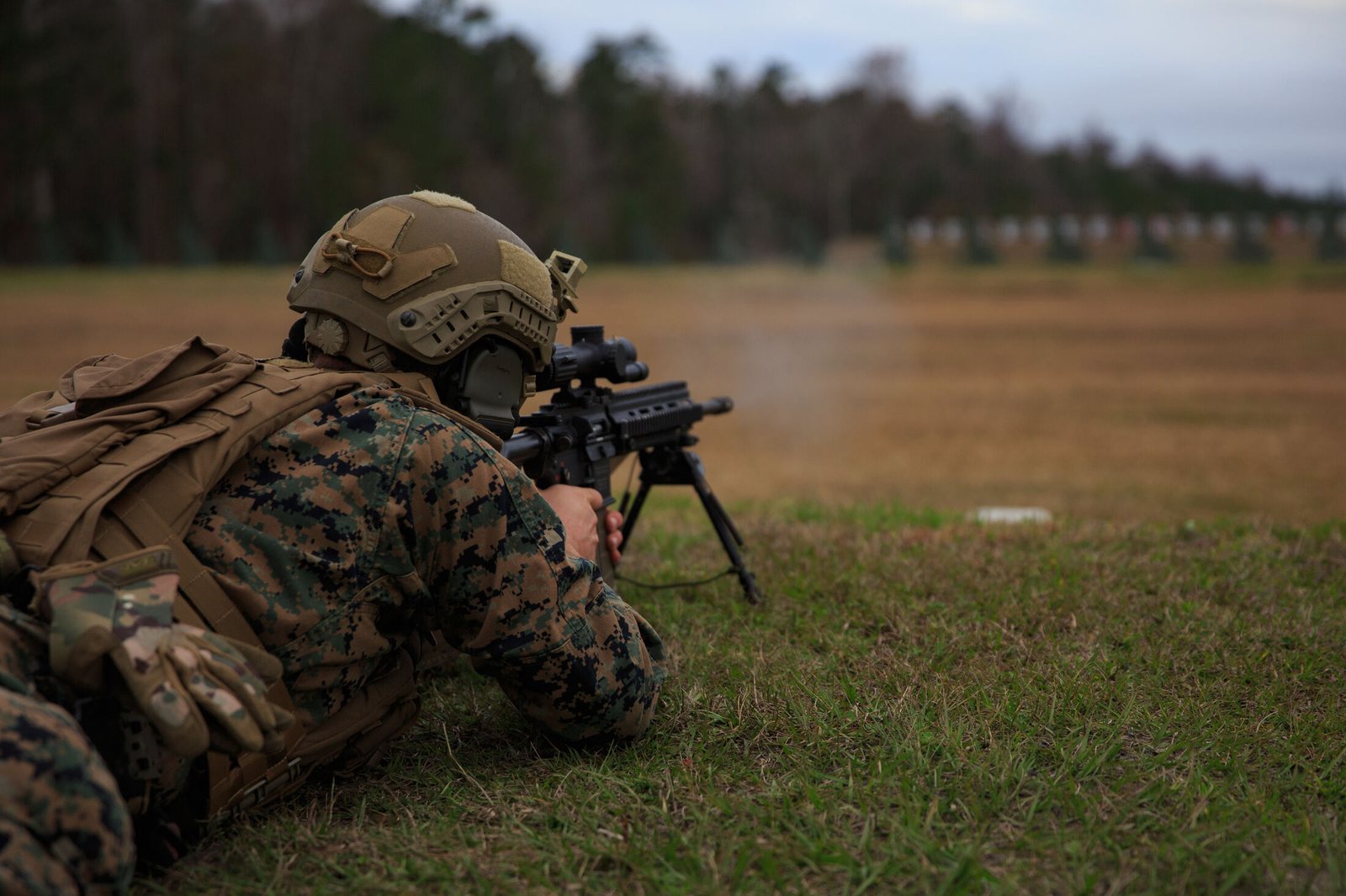 A Marine in the prone position firing a rifle on a grass range
