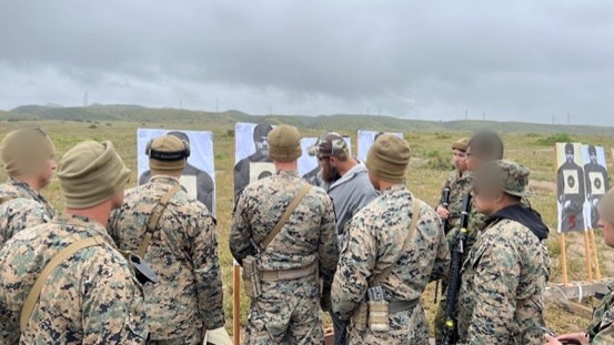 An instructor talking a class through their targets on the range; faces blurred