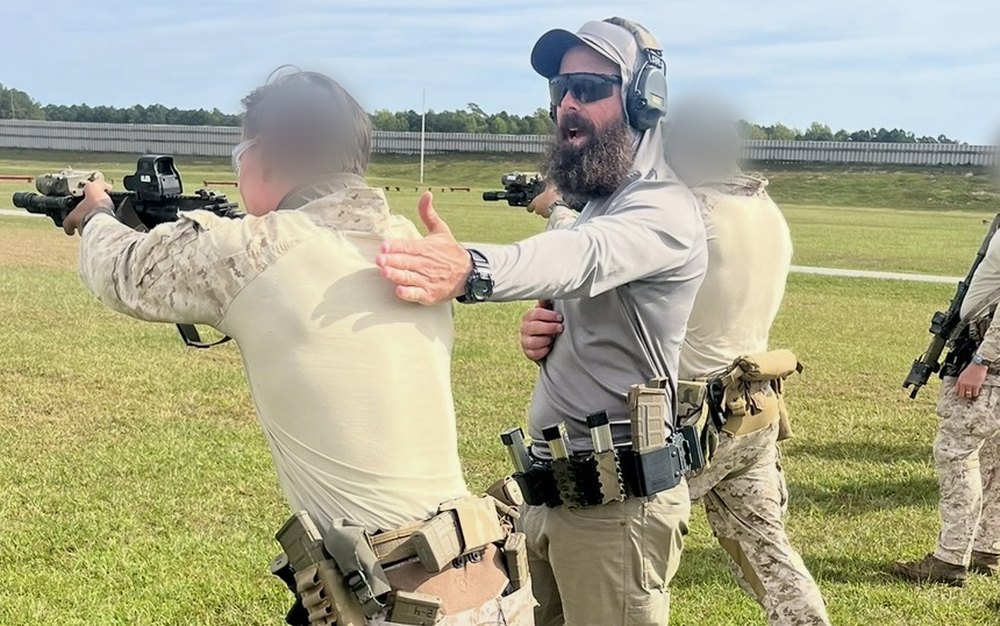 A JMAP instructor coaching a service member on the firing line; faces blurred